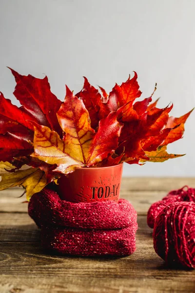 autumn leaves in a mug with tangles of yarn