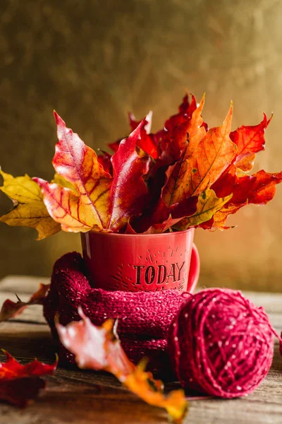 autumn leaves in a mug with tangles of yarn Golden background