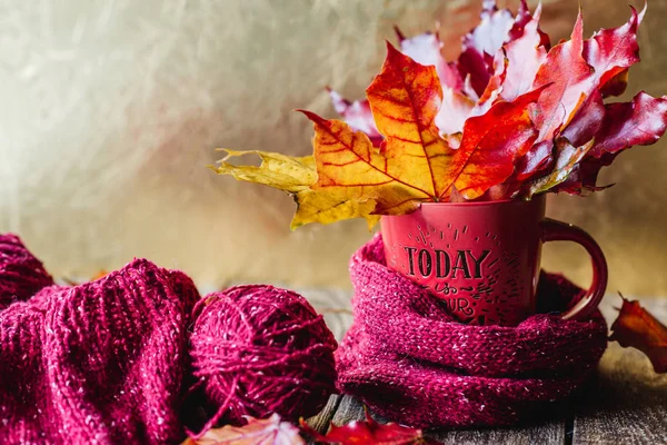 autumn leaves in a mug with tangles of yarn Golden background