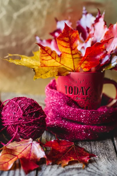 autumn leaves in a mug with tangles of yarn Golden background