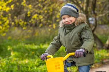 neşeli çocuk yeşil ceketli sarı bisiklet sürmek