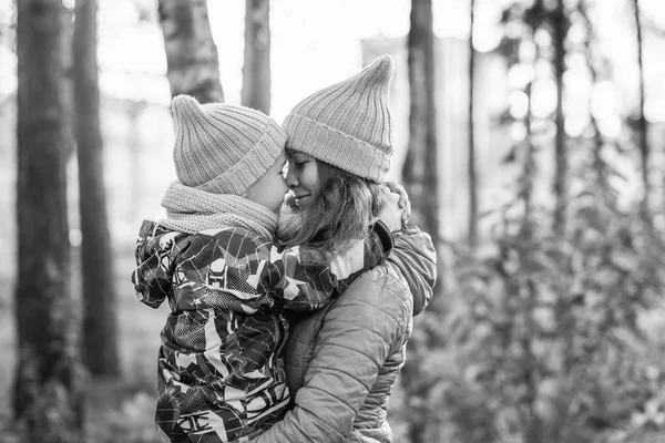 mom in a yellow hat and a blue jacket hugs her son in a yellow hat and a blue jacket autumn forest