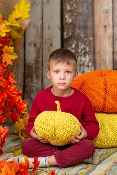 Um menino em uma camisola vermelha com uma abóbora amarela — Fotografia de Stock