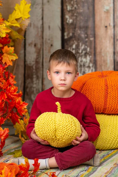 Un garçon en pull rouge avec une citrouille jaune — Photo