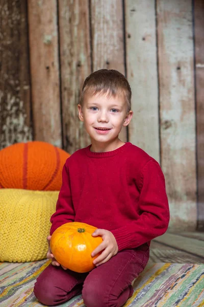 Хлопчик в червоному светрі з апельсиновим гарбузом — стокове фото