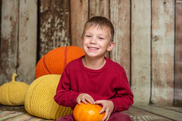 Un garçon en pull rouge avec une citrouille orange — Photo