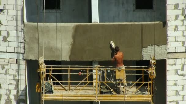 Building City The plaster works applies a solution of cement and speaks on his mobile phone — Stock Video