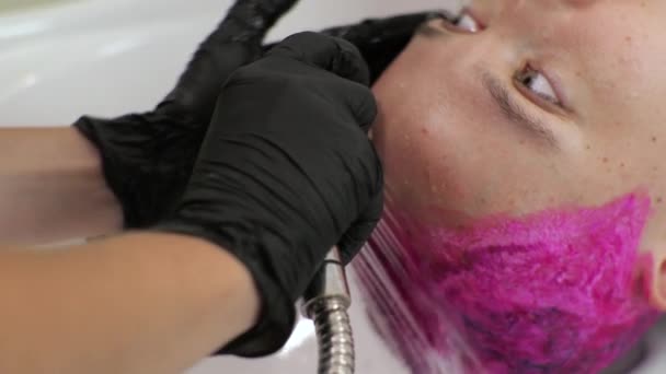 Kadeřník umývá ženské vlasy z růžového barviva. Domácí salon během epidemie. — Stock video