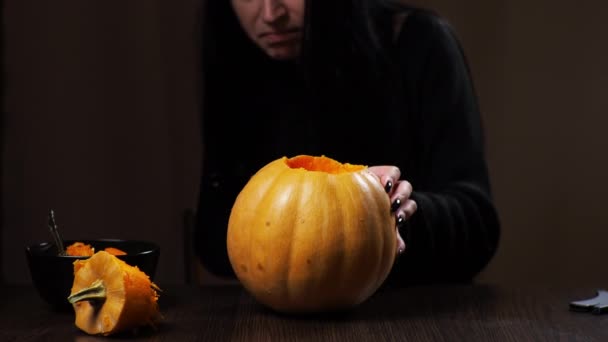 Junge brünette Frau schnitzt einen Kürbis für Halloween Vorbereitung für die Feiertage — Stockvideo