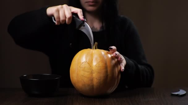 Junge brünette Frau schnitzt einen Kürbis für Halloween Vorbereitung für die Feiertage — Stockvideo