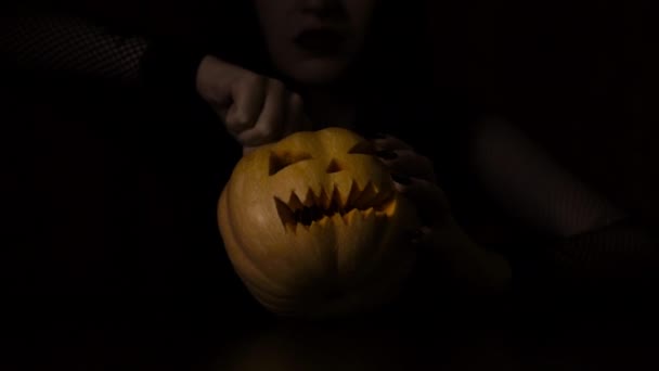 Young girl lights a candle in a pumpkin Halloween holiday Isolated black background — Stock Video