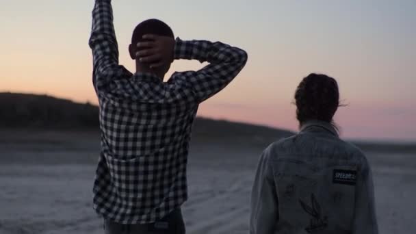 Vue sur la plage depuis l'arrière Quelques jeunes amoureux marchent le long de la plage minérale Nuit — Video