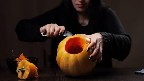 Young brunette woman carves a pumpkin for Halloween Preparation — Stock Photo, Image