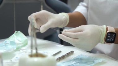 Genç kadın dişçi hasta için enstrümanı hazırlar.