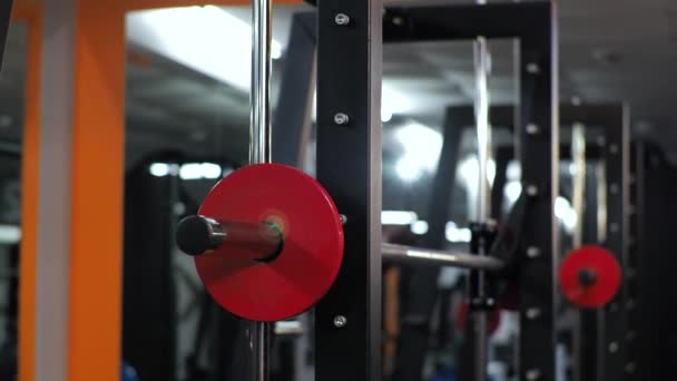 Молодой человек тренируется в спортзале кладет тяжелые диски на тренажер — стоковое видео
