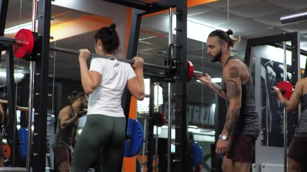 Gym Funny man is training an aspiring young woman Teaches you to swing legs with squats Motivates — Stock Footage Gym Funny man is training an aspiring young woman Teaches you to swing legs with squats Motivates Royalty Free Stock Video