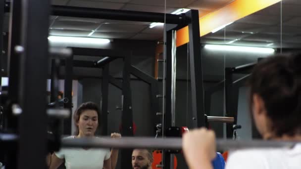 Gimnasio Divertido hombre está entrenando a una aspirante a mujer joven le enseña a balancear las piernas con sentadillas Motiva — Vídeos de Stock