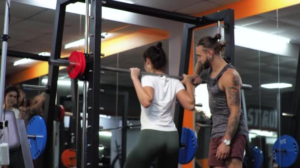 Ginásio Homem engraçado está treinando uma jovem aspirante Ensina você a balançar as pernas com agachamentos Motiva — Vídeo de Stock