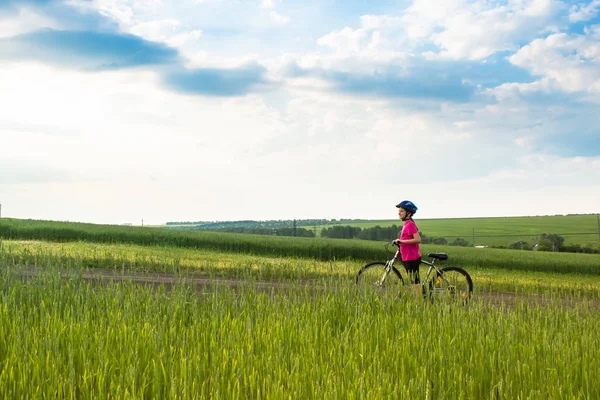 Sporty girl with bicycle in green field. — Stock Photo, Image