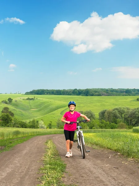 Ragazza sportiva con bicicletta in campo verde . — Foto Stock