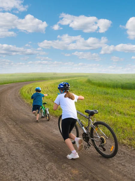 Sporty kids walking uphill with bikes — Stock Photo, Image