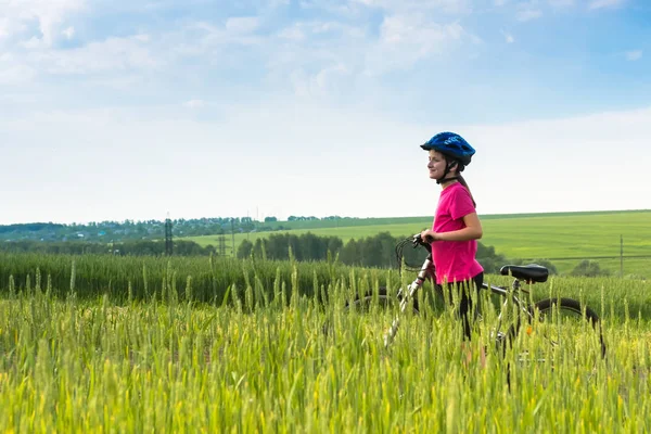 Ragazza sportiva con bicicletta in campo verde . — Foto Stock