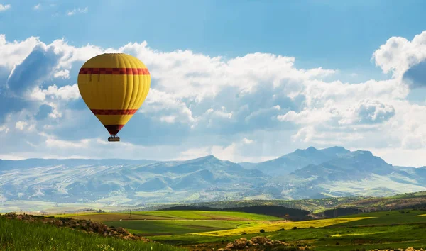 Pallone aerostatico colorato che sorvola il campo verde — Foto Stock