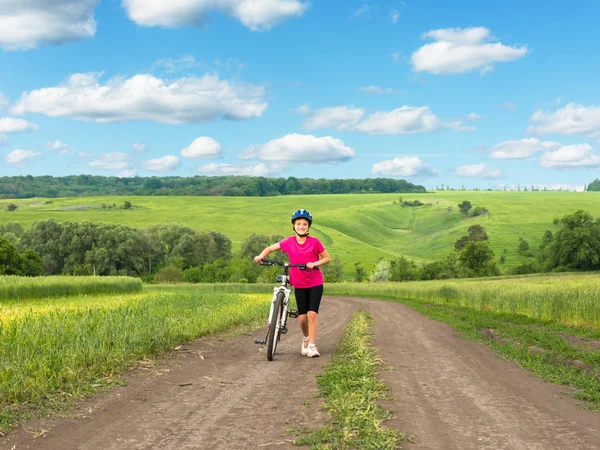 Girl on a bicycle in rural landscape — Stock Photo, Image