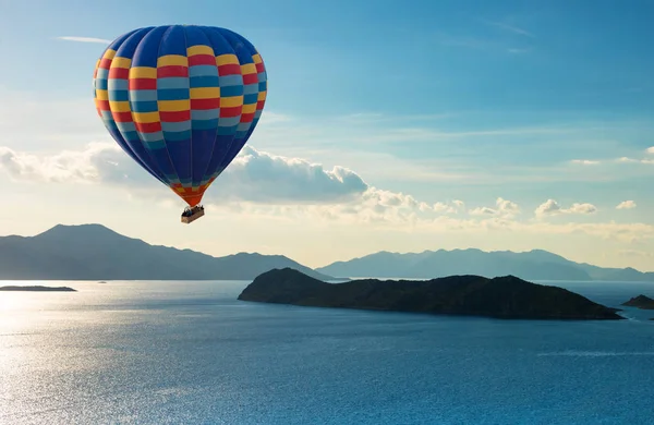 Balão de ar quente colorido voar sobre o mar azul — Fotografia de Stock