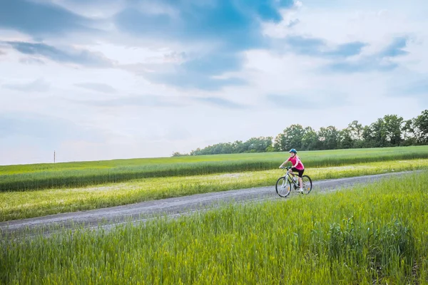 Sporty girl with bicycle in green field. — Stock Photo, Image