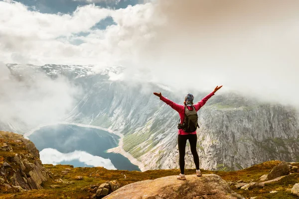 Junge Frau mit Rucksack steht an der Fjordküste — Stockfoto