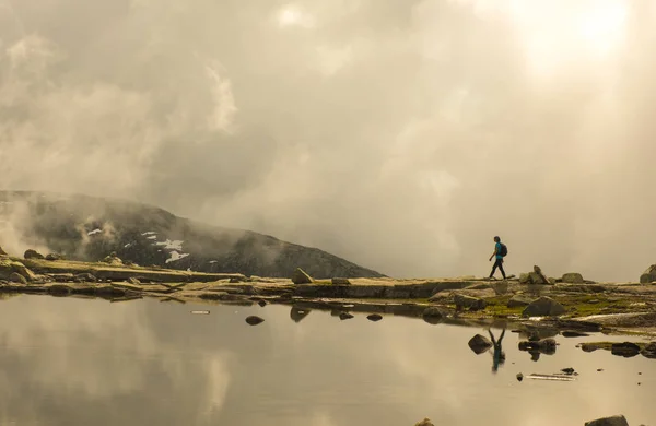 Silueta de mochilero caminando hacia el borde del lago rocoso. Países Bajos — Foto de Stock