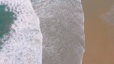 4k Havadan deniz dalgalarının görüntüsü sarı kumsalda kırılıyor