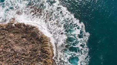 4k Havadan deniz dalgalarının görüntüsü taştan sahilde kırılıyor