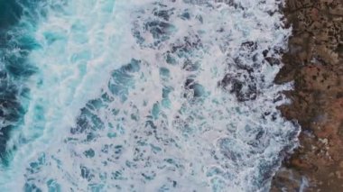 4k Havadan deniz dalgalarının görüntüsü taştan sahilde kırılıyor