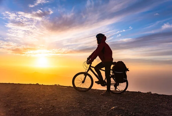 Mountain bicycle rider with backpack travels over sunrise background — Stock Photo, Image
