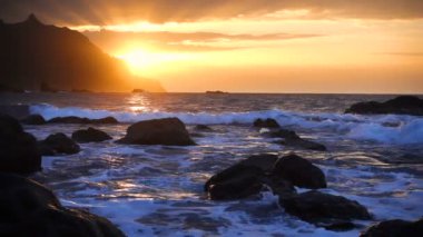 Okyanus dalgaları gün batımında kayalara çarpar Playa Benijo plajı, Tenerife, Kanarya