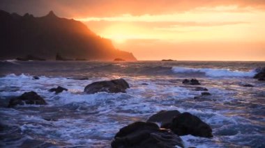 Okyanus dalgaları gün batımında kayalara çarpar Playa Benijo plajı, Tenerife, Kanarya