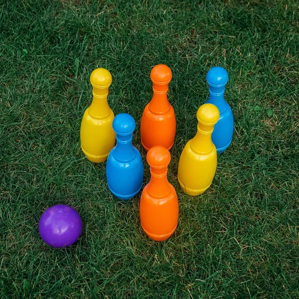 子供たちの緑の芝生の上でボーリングを再生するように設定します ボールと色のピン 子供のおもちゃだ カラフルなプラスチック製のピンをボウリング 積極的で面白い子供時代のコンセプト — ストック写真