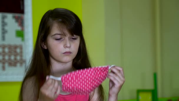 Маленькая серьезная девочка надевает медицинскую маску . — стоковое видео