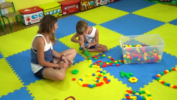 Kleiner Sohn mit Mama spielt Konstrukteur auf dem Teppich-Puzzle im Spielzimmer. — Stockvideo