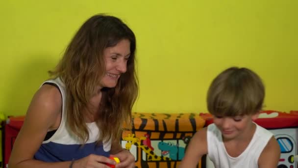 Kleiner Sohn mit Mama spielt Konstrukteur auf dem Teppich-Puzzle im Spielzimmer. — Stockvideo