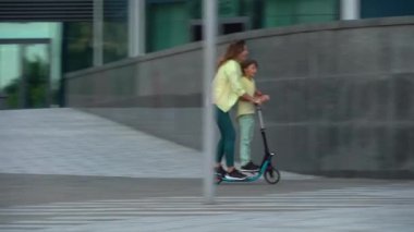 Anne ve oğlu birlikte scooter kullanıyor. Anne ve oğlu yazın eğleniyor. Scooter 'da aile değerleri birlikte zaman geçirirken aile mobilete biner..
