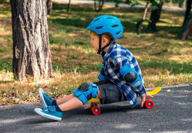 Mutlu küçük çocuk sarı bir kaykay üzerinde bir gezintiye hazırlanıyor