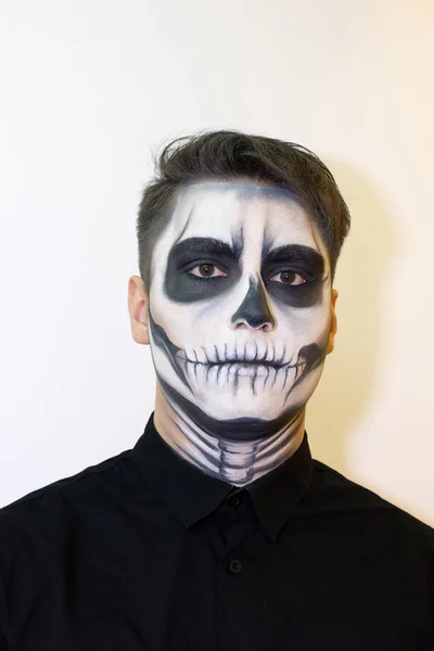 man in make-up Halloween. drawing a vampire, skeleton on his face. Close-up photo