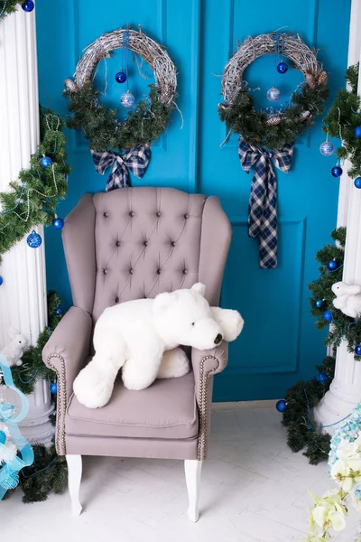New Year\'s interior. Christmas decorations. Luxury , bright, clean bright beautiful home interiors. Armchair with a bear and blue doors.