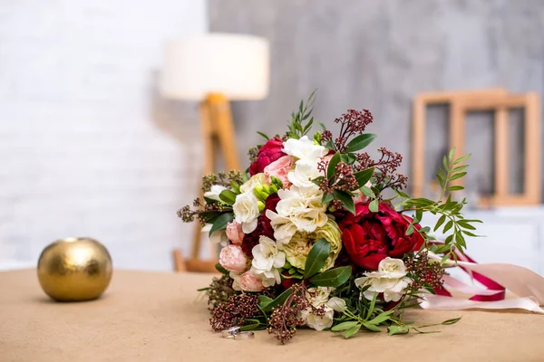 beautiful modern wedding bouquet on the table. with wedding rings near the bouquet. Against the gray wall. beautiful interior