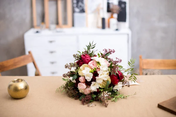桌上美丽的现代婚礼花束 花束附近有结婚戒指 在灰色的墙上 美丽的内饰 — 图库照片