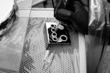 siyah beyaz fotoğraf. Ana dövmeci dövme için Araçlar hazırlar.