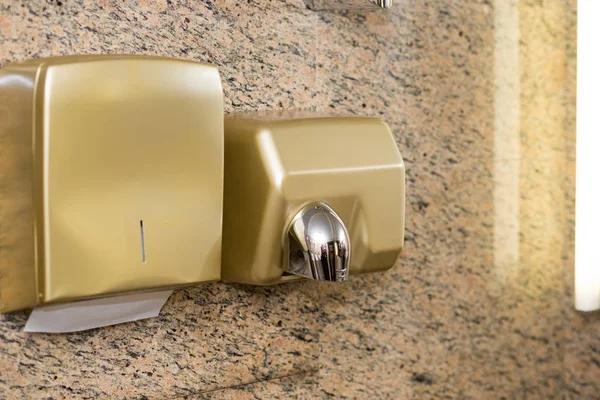 Paper Dispenser and hand dryer on the wall in public toilet.